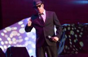 Blues Brothers Tribute Band singer belts out a tune on stage at a corporate event.